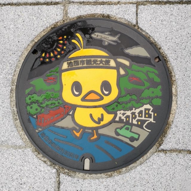 A colorful manhole cover in Ikeda featuring the Cup Noodles mascot chick, Hiyoko chan