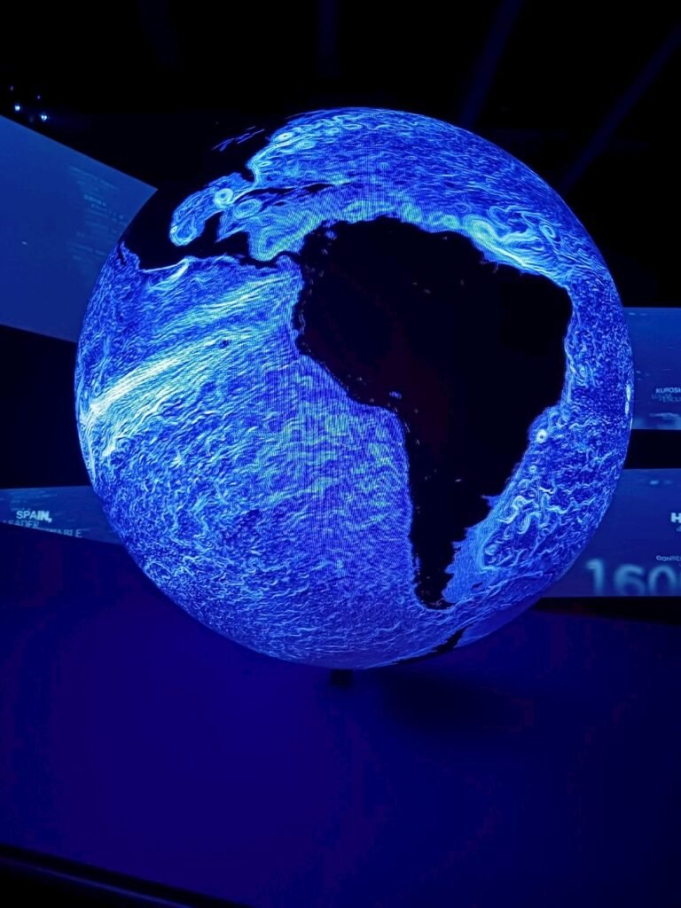 A glowing digital globe in blue tones showcasing ocean currents and environmental data.