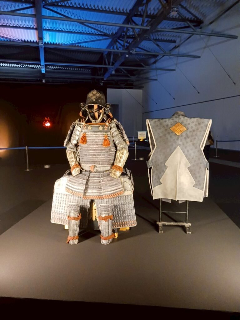 Display of samurai armor set under spotlights inside a pavilion